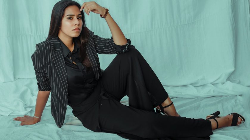 woman in black and white stripe dress shirt and black pants sitting on white bed