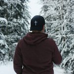 person in red hoodie and black cap standing on snow covered ground