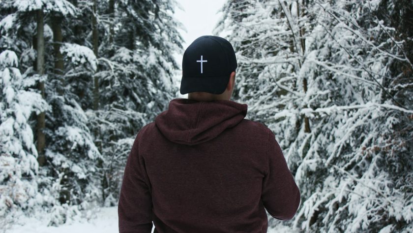person in red hoodie and black cap standing on snow covered ground