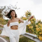 a woman in a white outfit is walking down a road