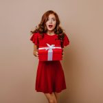 a woman in a red dress holding a red gift box