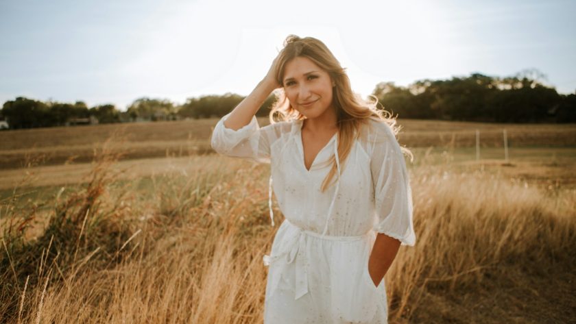 woman in white dress standing on brown grass field during daytime